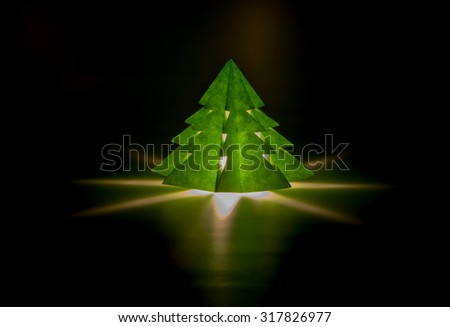 Small lantern in a form of Christmas tree with a candle inside in a dark room