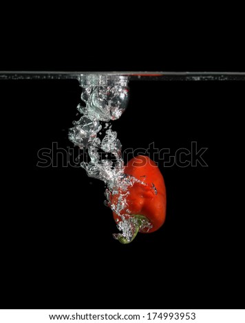 Fresh red paprika splash in water on black background