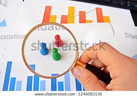 A young man is holding a magnifying glass in his hand, looking at statistic figures - a business concept on the subject of sampling and selecting the right target group and examining it Photo stock © 