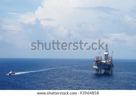 Jack up drilling rig and crew boat in the middle of the ocean