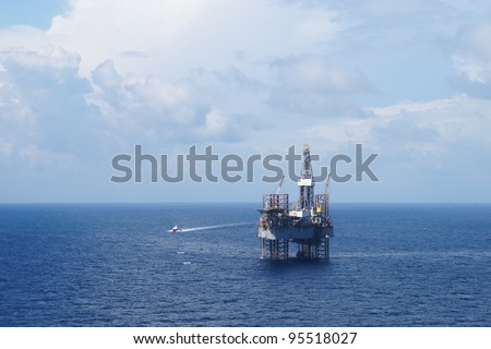 Jack up drilling rig and crew boat on sunny day