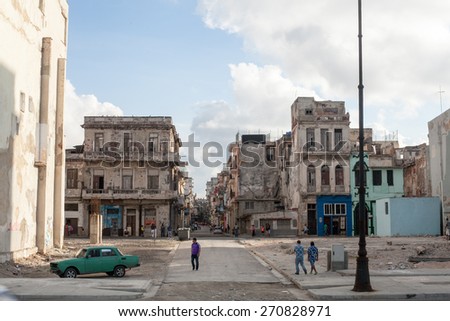 Havana, Cuba - 18 January, 2015 - people walking on a street full of crumbling buildings.