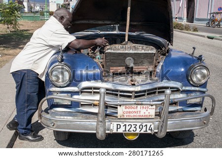 Santiago, Cuba - 25 January, 2015 - an old man tries to repair his broken car in a street.