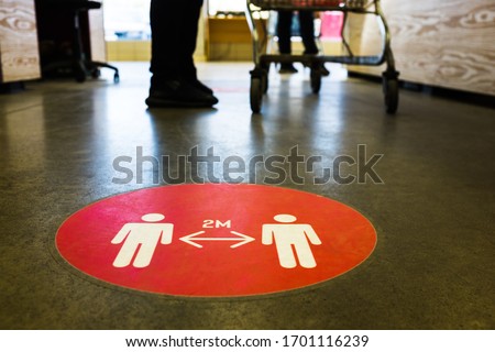 Red round sign printed on ground at supermarket cash desk register informing people to keep 2 meter 6 feet distance from each other,prevent spreading Coronavirus COVID-19 virus disease infection,UKUS