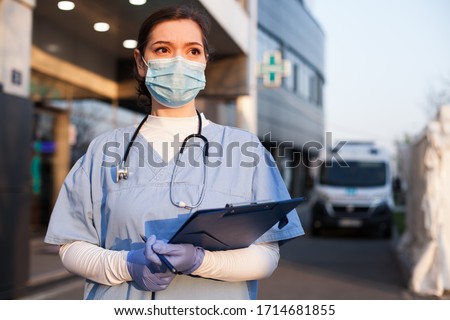 Young female EMS key worker doctor in front of healthcare ICU facility,wearing protective PPE face mask equipment,holding medical lab patient health check form,UK US COVID-19 pandemic outbreak crisis  Zdjęcia stock © 