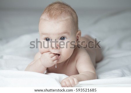 Curious baby with hand stuck in mouth sucking fingers drooling, teething infant trying to soothe inflamed gums and itching growing teeth biting hand and fingers, newborn child pain and discomfort  商業照片 © 