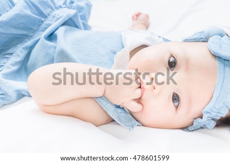 a cute asian baby is sucking her finger which is normal development in oral stage 商業照片 © 