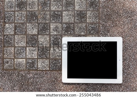 Tablet white frame and black screen put on chessboard in public park