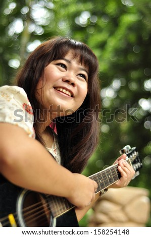 Asian woman with  guitar in garden