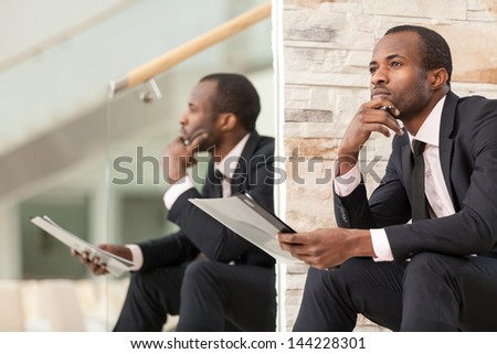 Businessman sits and thinks with his chin on his hand