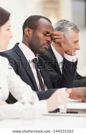 Portrait of a tired young business man bored during meeting