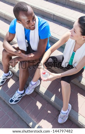 After the training. Young interracial couplesitting at stairs and talking after the training