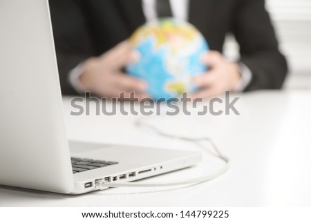 hands holding earth globe that connected to laptop computer