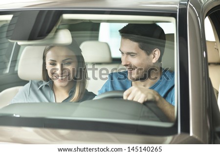 Look at this console! Beautiful young couple sitting at the front seat of the car checking out the side panel