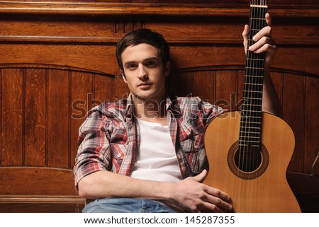 Men and his guitar. Handsome young men sitting on the floor and holding his guitar