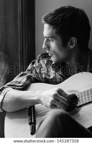 Looking for inspiration outside. Black and white shot of men playing guitar and looking through window
