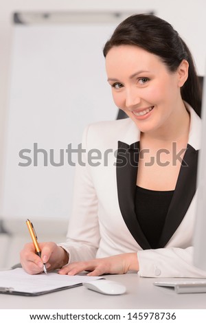I have so many ideas. Beautiful middle-aged businesswoman sitting at her working place making notes in her sketchpad