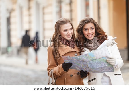I think we should go there. Two beautiful young women holding a map and pointing away