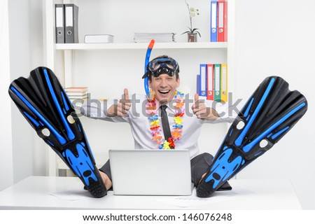 Ready for vacation.  Cheerful businessman in flippers and snorkel sitting at his working place and smiling at camera