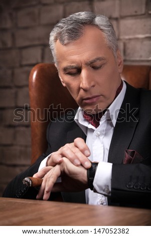 He knows how important time is. Worried mature businessman checking the time