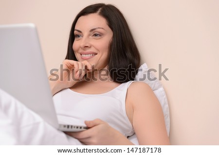 Working at her day off. Beautiful middle-aged women lying on the sofa and working at the computer