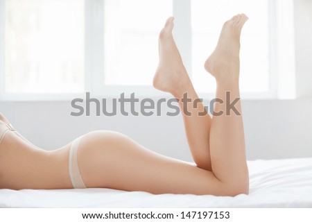 Perfect female body. Cropped image of beautiful women lying on front with her feet up