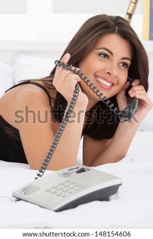 Talking with boyfriend. Attractive young women talking at phone while lying on the sofa