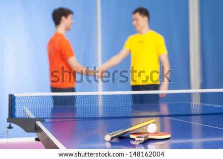 Good game! Two young men in sports clothing handshaking near the tennis table