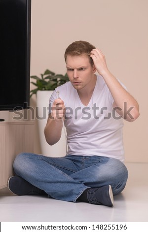 Men with TV cable. Frustrated young men holding a TV cable and looking at it with surprise