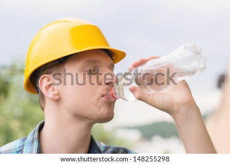Handyman drinking water. Side view of tired handyman drinking water with his eyes closed