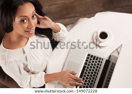 Beauty with laptop.  Top view of beautiful African descent women working on laptop and looking at camera