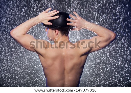Perfect body. Rear view of young men in black fedora standing under the rain