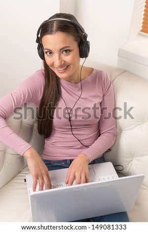 Women with laptop. Top view of cheerful young women in headphones working at the computer while sitting on the couch