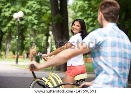 Bike ride. Cheerful young couple riding bikes in park
