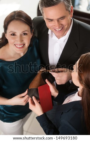 Couple in furniture store. Top view of cheerful middle-aged couple choosing fabric and communicating with sales clerk