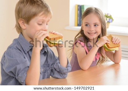 Children eating sandwiches. Two cheerful children eating sandwiches and smiling