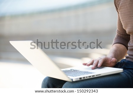 Working outdoors. Cropped image of cheerful young man working on laptop outdoors