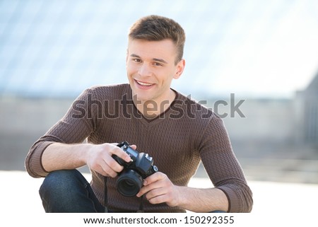 Young photographer. Cheerful young photographer holding camera and smiling