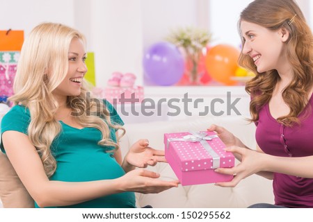 Baby shower. Beautiful pregnant woman receiving gift from her friend