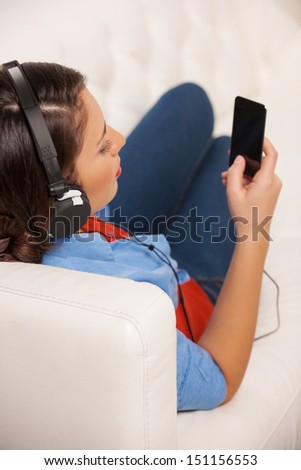 Woman listening to the music. Rear view of beautiful young woman in headphones listening to the music
