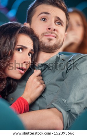 Horror movie. Terrified young couple hugging while watching movie the cinema