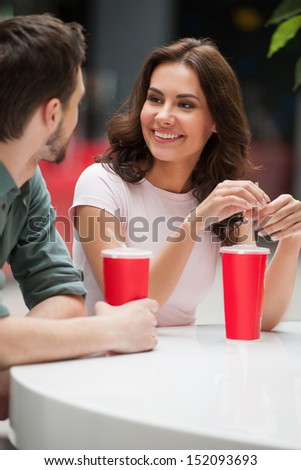 Couple talking. Cheerful young couple talking and drinking soda