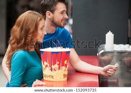 Loving couple in bar. Young loving couple buying popcorn and soda at the cinema bar