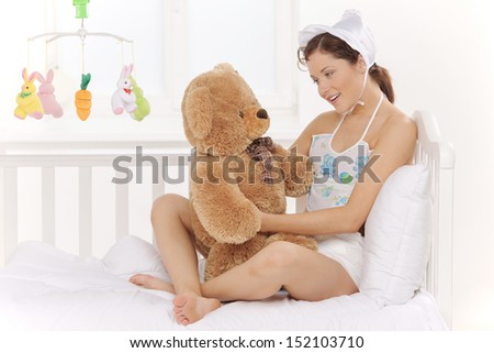 Big baby. Infant young woman in baby wear and diapers holding teddy bears and smiling