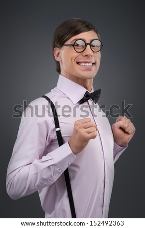 Cheerful nerd. Young cheerful nerd man smiling while isolated on grey