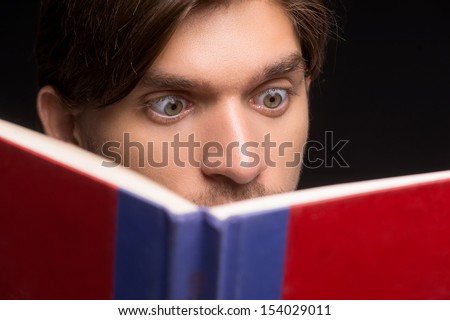 Shocking book. Portrait of surprised young men reading book while isolated on black