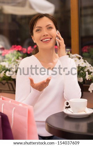 Women with mobile phone. Beautiful young women talking on the mobile phone while sitting at the restaurant