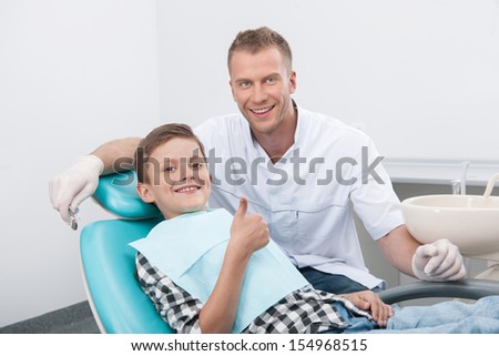 Patient at dentist office. Dentist and little patient looking at camera and smiling