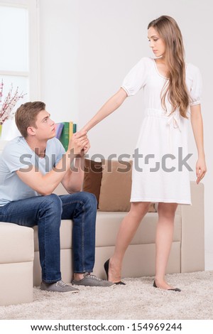 Relationship difficulties. Sad young man holding his girlfriend hand while sitting on the couch