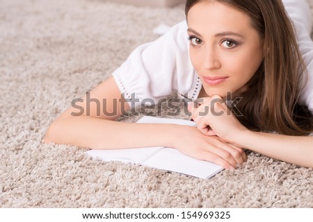 Girl with note pad. Beautiful young woman lying on the floor and writing something in her note pad